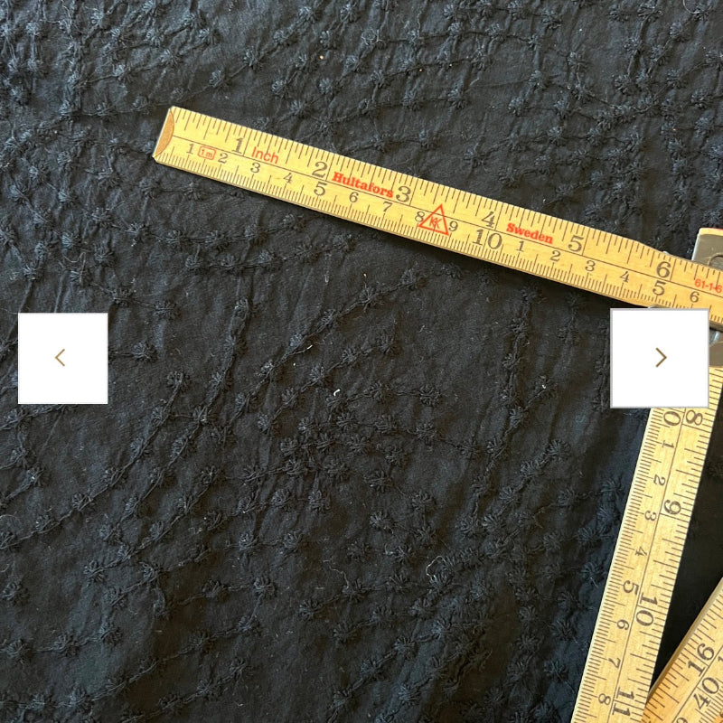 Black textured fabric with a ruler for scale on a dark background